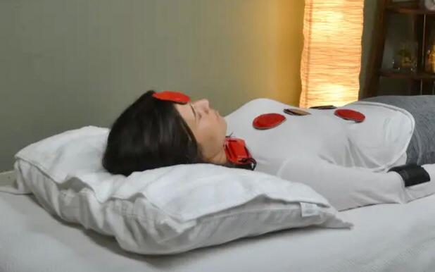 A woman laying on a bed with biomagnet pairs placed on her upper body.